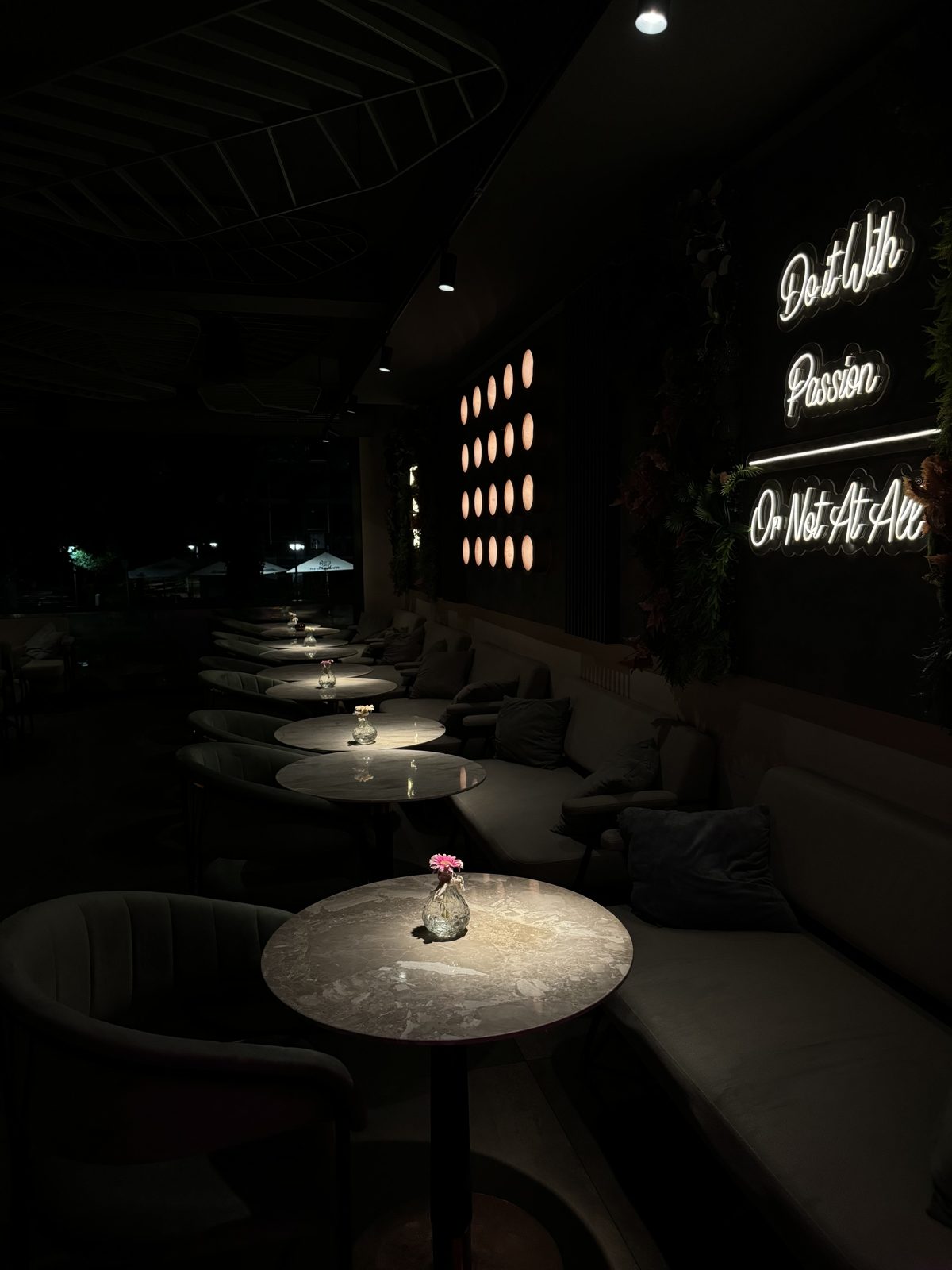 Lounge mit Marmortischen und Neon-Schriftzug „Do it with Passion or not at all“
